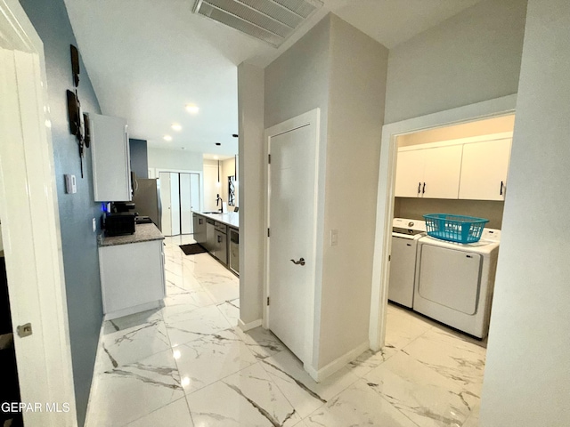 kitchen featuring sink, washing machine and dryer, and white cabinets