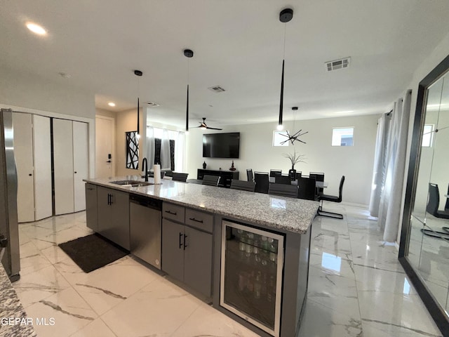 kitchen featuring pendant lighting, sink, wine cooler, stainless steel dishwasher, and light stone countertops