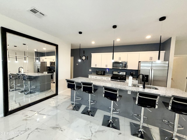 kitchen with white cabinetry, appliances with stainless steel finishes, a breakfast bar area, and a large island with sink