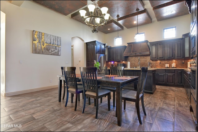 dining space with dark wood-type flooring, a high ceiling, coffered ceiling, beamed ceiling, and a chandelier