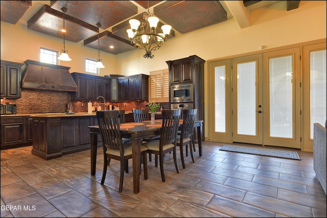 dining area featuring beamed ceiling, a high ceiling, coffered ceiling, an inviting chandelier, and french doors