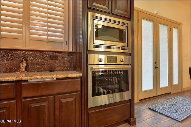 kitchen featuring light stone counters, decorative backsplash, stainless steel appliances, and french doors