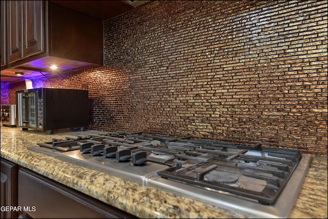 details with stainless steel gas stovetop and dark brown cabinetry