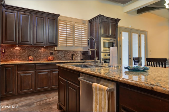 kitchen with appliances with stainless steel finishes, beamed ceiling, sink, decorative backsplash, and dark brown cabinets