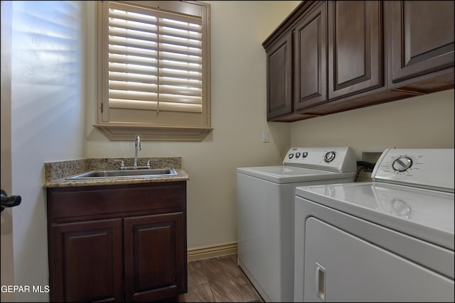 laundry room featuring cabinets, dark hardwood / wood-style flooring, sink, and washer and clothes dryer