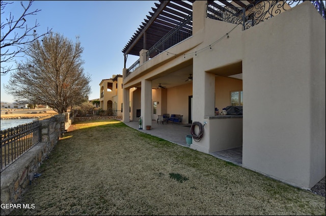 view of yard with ceiling fan, a patio, a balcony, and a water view