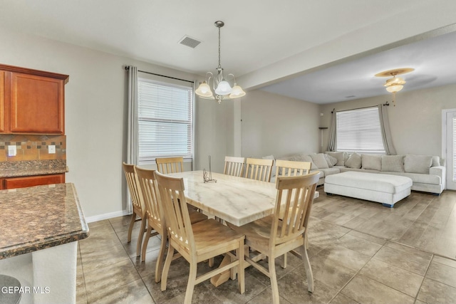 dining space featuring a healthy amount of sunlight, light tile patterned floors, and a chandelier