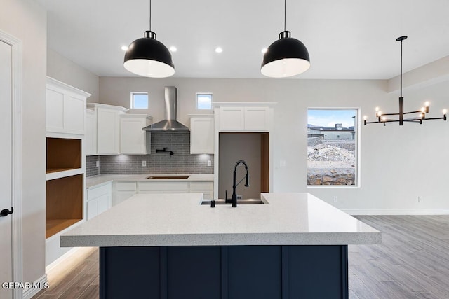 kitchen featuring white cabinetry, wall chimney range hood, and hanging light fixtures