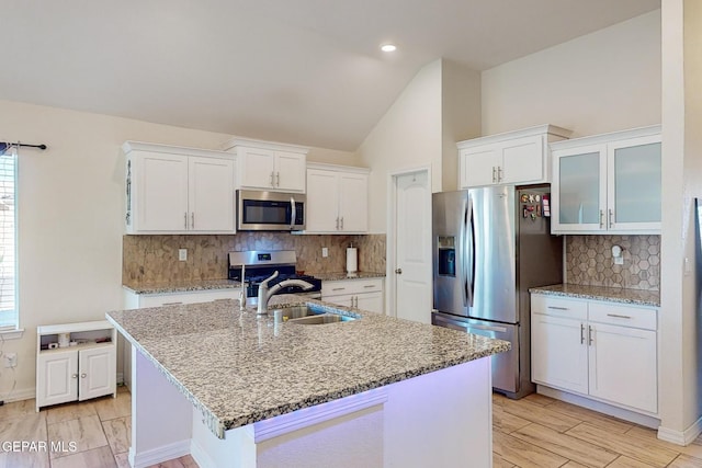 kitchen with stainless steel appliances, sink, a kitchen island with sink, and white cabinets