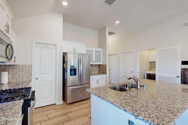 kitchen with sink, a center island with sink, white cabinets, and appliances with stainless steel finishes