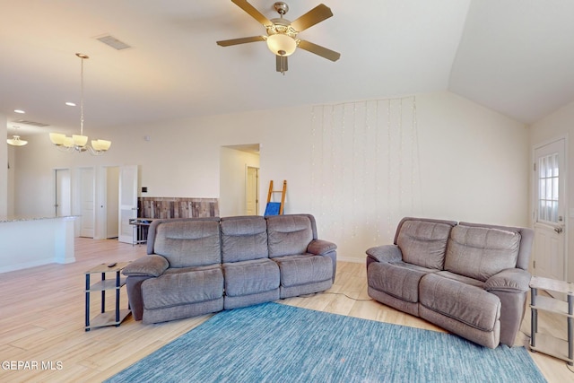 living room featuring ceiling fan with notable chandelier, light hardwood / wood-style floors, and vaulted ceiling