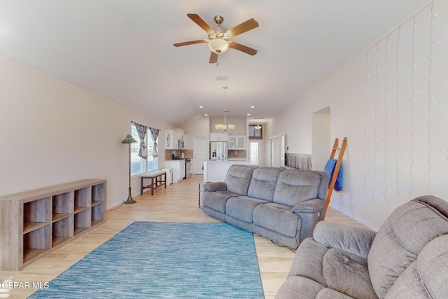 living room featuring lofted ceiling, ceiling fan with notable chandelier, and light hardwood / wood-style floors