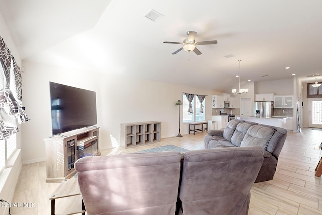 living room with lofted ceiling, ceiling fan with notable chandelier, and a fireplace