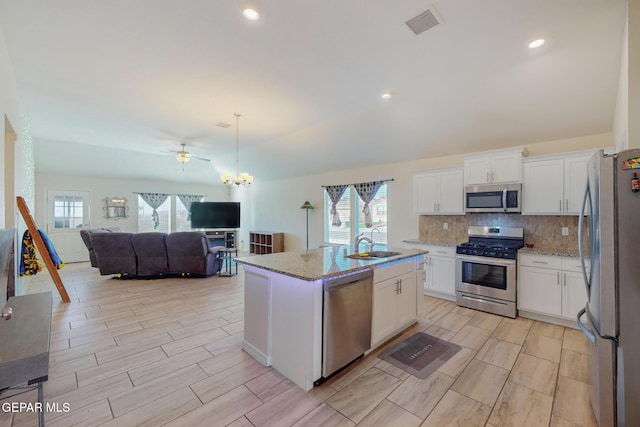 kitchen featuring stainless steel appliances, an island with sink, hanging light fixtures, and white cabinets