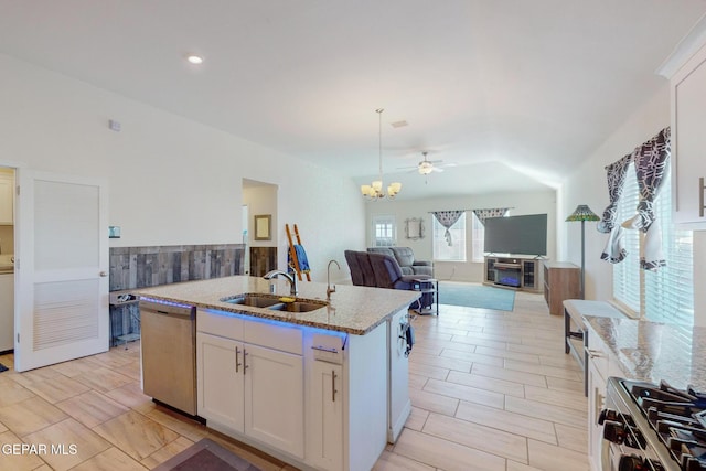 kitchen featuring appliances with stainless steel finishes, white cabinetry, an island with sink, sink, and light stone counters