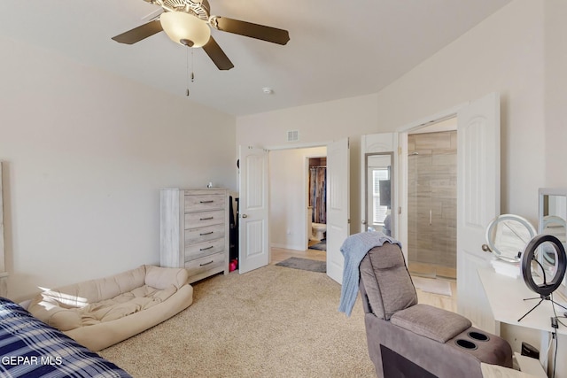 bedroom featuring connected bathroom, light colored carpet, and ceiling fan