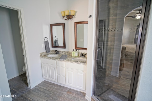 bathroom with ceiling fan, vanity, toilet, and a shower with shower door