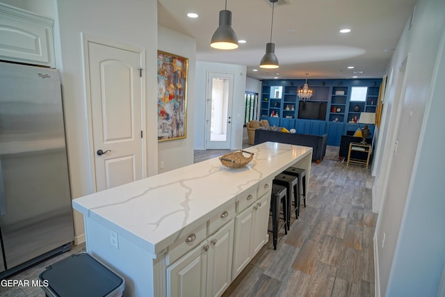 kitchen with pendant lighting, stainless steel fridge, a breakfast bar, a center island, and built in shelves