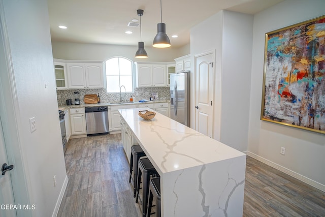 kitchen with sink, white cabinetry, hanging light fixtures, stainless steel appliances, and a center island