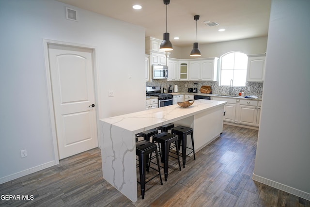 kitchen with light stone counters, a kitchen breakfast bar, a kitchen island, stainless steel appliances, and white cabinets