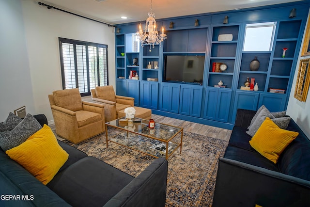 living room featuring built in shelves, an inviting chandelier, and hardwood / wood-style flooring