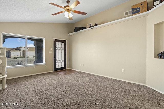 foyer entrance with ceiling fan, vaulted ceiling, a textured ceiling, and dark colored carpet