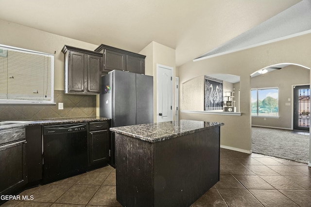 kitchen featuring stainless steel fridge, dark tile patterned floors, black dishwasher, tasteful backsplash, and a kitchen island