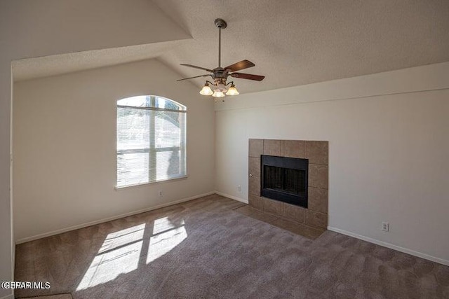 unfurnished living room featuring vaulted ceiling, a tile fireplace, ceiling fan, and carpet flooring