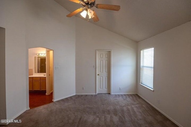 unfurnished bedroom featuring lofted ceiling, connected bathroom, ceiling fan, and dark colored carpet