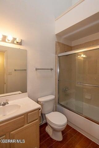 full bathroom featuring vanity, combined bath / shower with glass door, and toilet