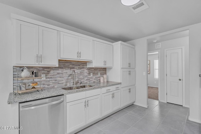 kitchen featuring white cabinetry, sink, stainless steel dishwasher, and light stone countertops