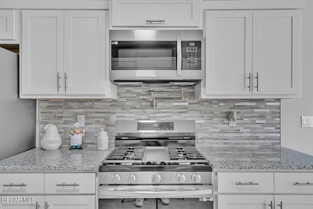 kitchen with stainless steel appliances, light stone countertops, decorative backsplash, and white cabinets