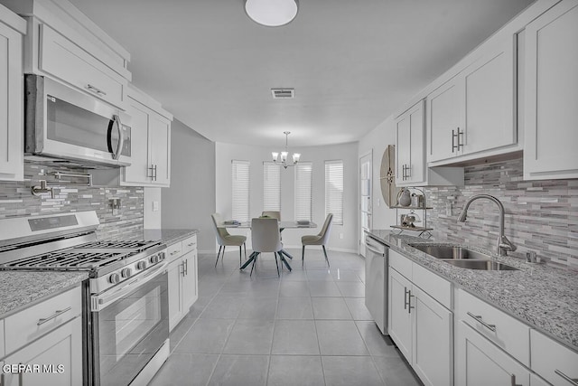 kitchen with white cabinetry, stainless steel appliances, sink, and light stone counters