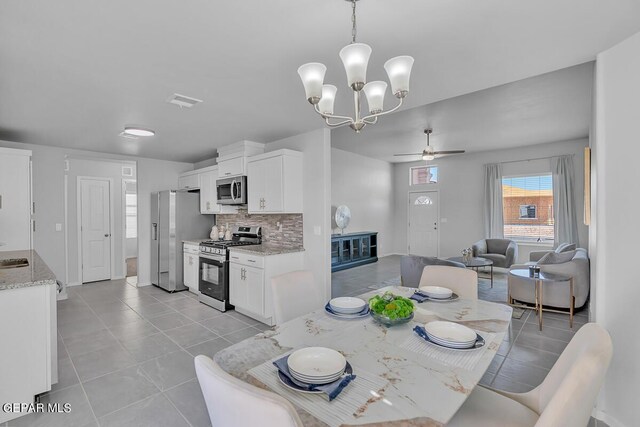 dining space with light tile patterned flooring and ceiling fan with notable chandelier