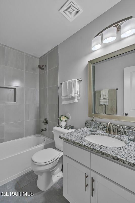 full bathroom with vanity, tiled shower / bath combo, tile patterned floors, and toilet