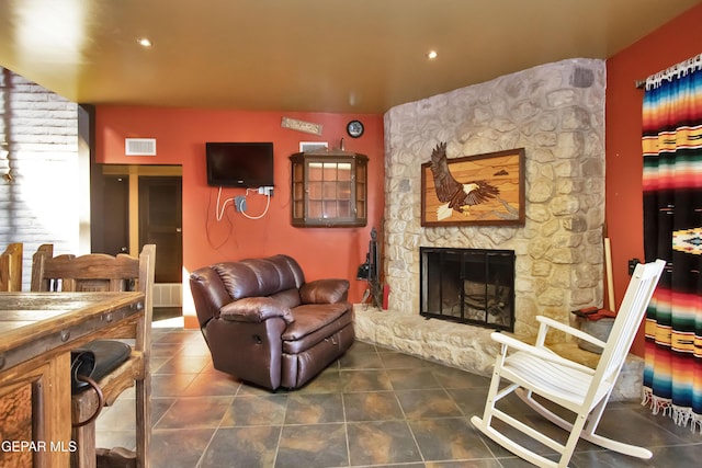 tiled living room featuring a stone fireplace