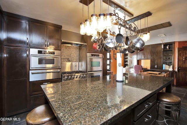 kitchen with dark brown cabinetry, a notable chandelier, a kitchen breakfast bar, and dark stone counters