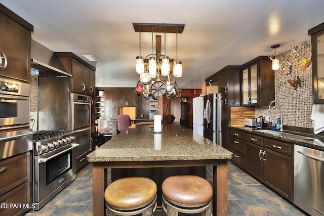 kitchen featuring appliances with stainless steel finishes, pendant lighting, tasteful backsplash, dark stone countertops, and a breakfast bar area