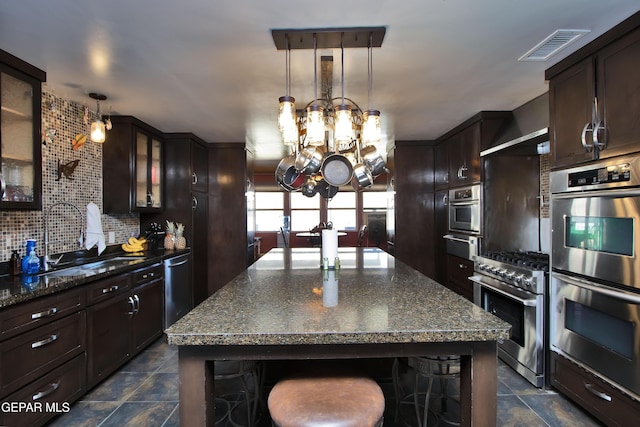 kitchen with sink, a breakfast bar, hanging light fixtures, stainless steel appliances, and a kitchen island