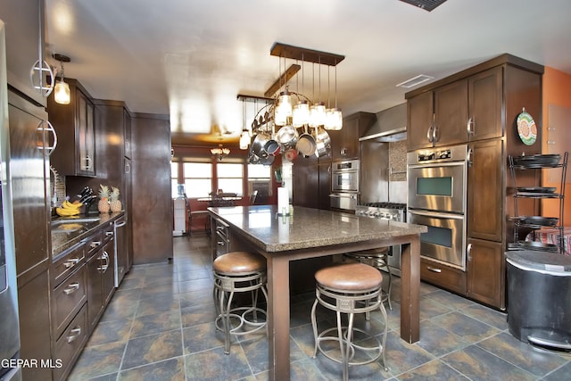 kitchen featuring a kitchen island, pendant lighting, dark stone countertops, a kitchen breakfast bar, and stainless steel double oven