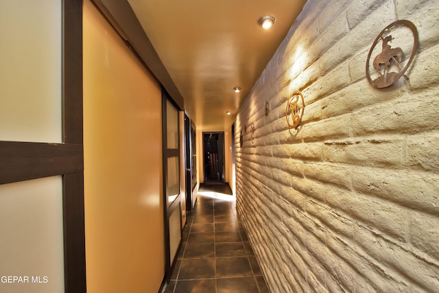 hallway with dark tile patterned floors and rustic walls