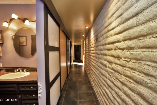 hall featuring sink and dark tile patterned flooring