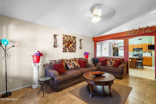 living room featuring vaulted ceiling, light tile patterned floors, ceiling fan, and a textured ceiling