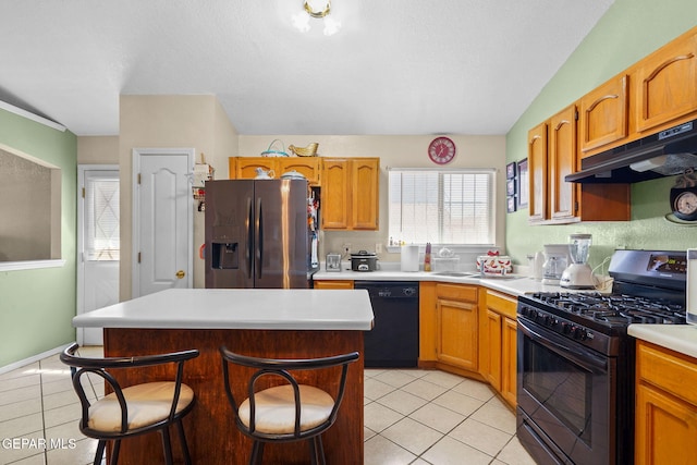 kitchen featuring light tile patterned floors, black appliances, a center island, and a kitchen bar