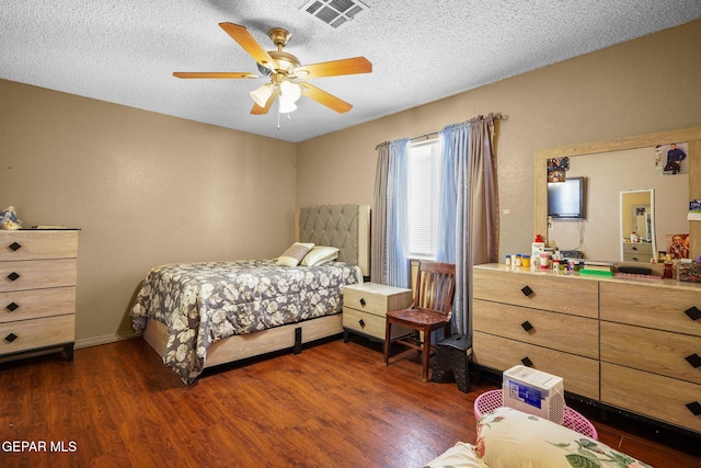 bedroom featuring ceiling fan, dark wood-type flooring, and a textured ceiling