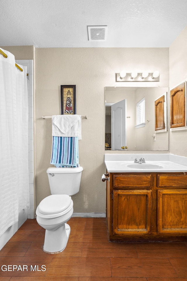 bathroom featuring vanity, hardwood / wood-style floors, a textured ceiling, and toilet