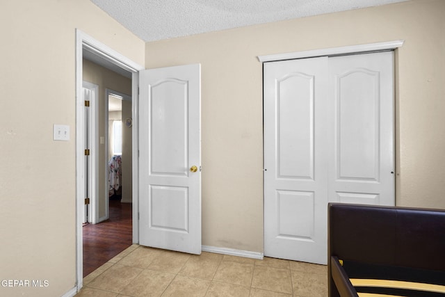 tiled bedroom with a closet and a textured ceiling