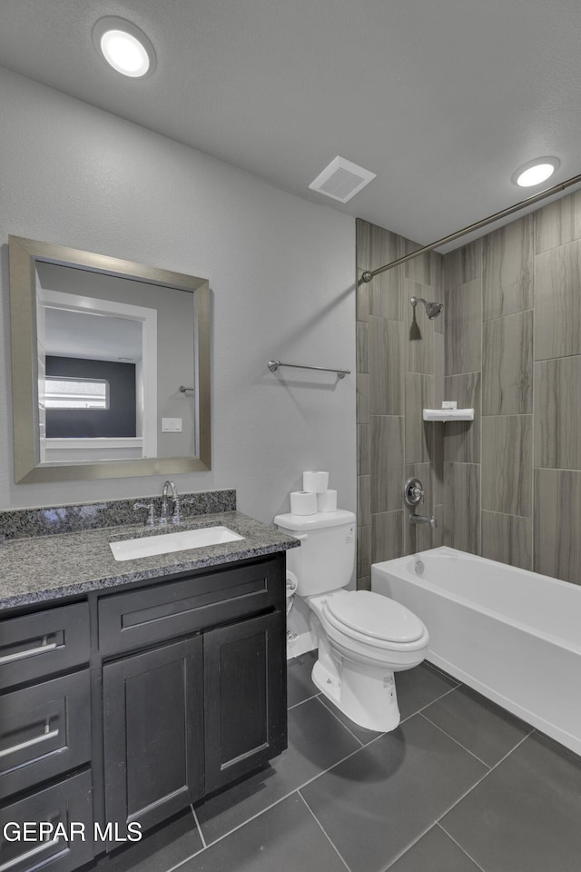 full bathroom with tiled shower / bath, vanity, tile patterned floors, and toilet