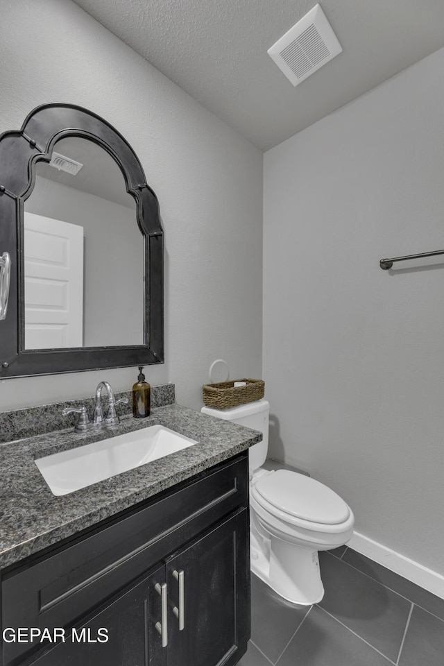 bathroom featuring tile patterned floors, toilet, vanity, and a textured ceiling