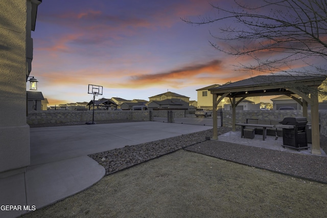 patio terrace at dusk with a gazebo, basketball court, and grilling area